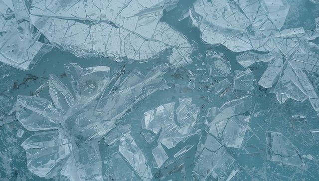 Fractured blue ice shards overhead view featuring crystal-like translucent frozen pond surface
