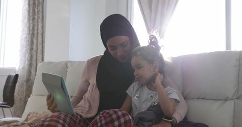 Mother and Daughter Bonding with Tablet Wearing Casual Outfits