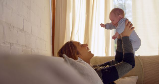 Smiling Mother Holding Baby at Home with Sunlight Through Curtains - Download Free Stock Images Pikwizard.com