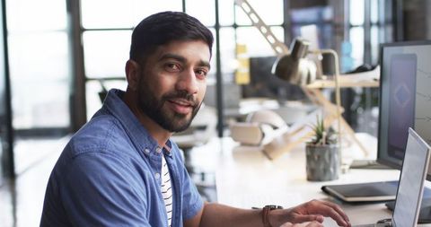Asian man typing at desk in modern office environment