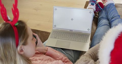 Holiday couch laptop mockup with cozy sweater, reindeer antlers and santa hat for seasonal streaming