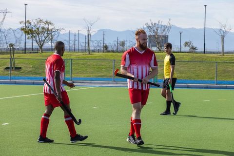 Male field hockey players competing on turf field