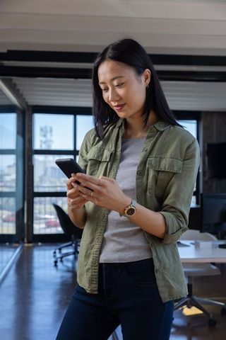 Asian Woman in Open-Plan Office Using Smartphone