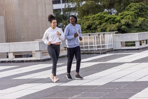 Two women walking on urban terrace in hoodies and sneakers, casual fitness friendship