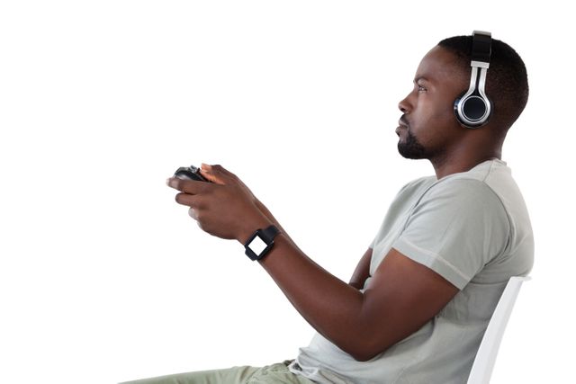 This image shows a man intensely playing a video game while wearing headphones. Ideal for use in articles about gaming culture, technology reviews, or advertisements for gaming accessories and consoles.