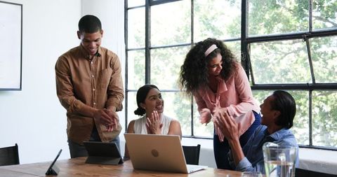 Happy Multiracial Team Collaborating and Celebrating in Bright Office