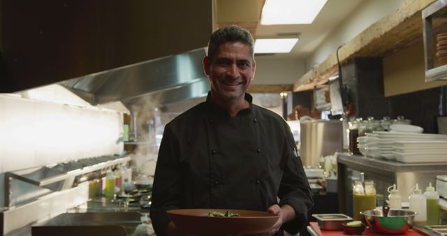 Smiling Chef in Professional Kitchen Holding Prepared Dish - Download Free Stock Images Pikwizard.com