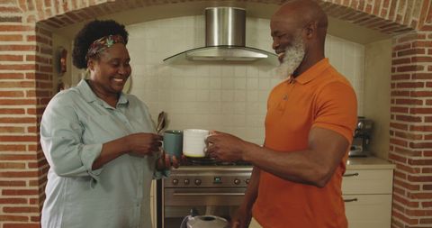 Joyful Senior Couple Toast with Coffee in Cozy Kitchen