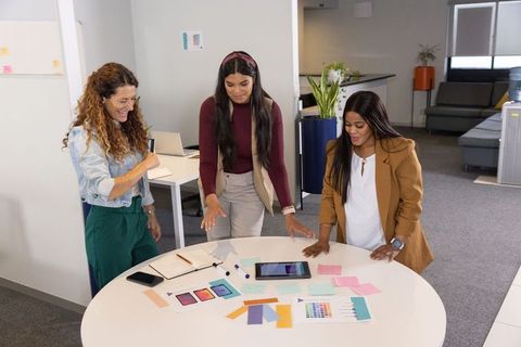 Female team collaborating on branding and color selection around round table in office