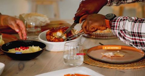 Black man carving roast chicken at family dinner table, sharing meal and togetherness
