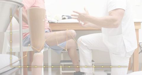 Kneeling clinician assessing patient with prosthetic leg during rehabilitation and fitting