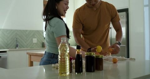 Couple preparing citrus on white kitchen island, modern home cooking and meal prep