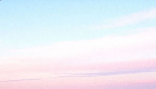 Soft pastel sunrise sky forming tranquil gradient with thin cloud streaks and open horizon