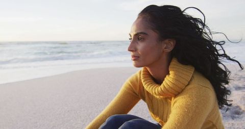 Serene Woman in Yellow Sweater at Sunset Beach