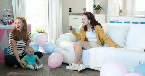 Women celebrating baby shower with balloons and laughter