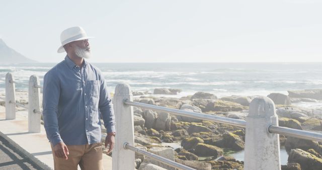 Senior Man Walking by Ocean in Sunshine Wearing White Hat - Download Free Stock Images Pikwizard.com