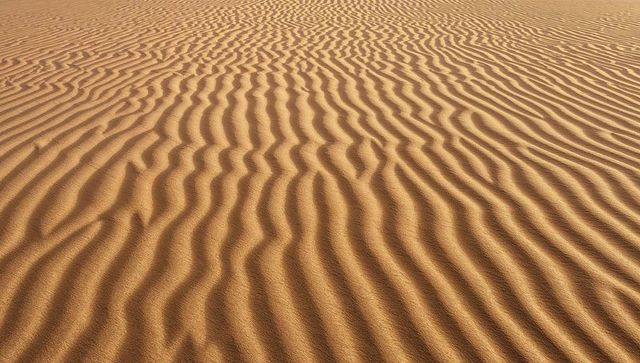 Golden sand ripples across wind-sculpted desert dunes textured abstract landscape