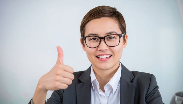 Smiling young professional giving thumbs up confident corporate headshot for branding