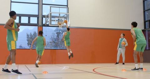 Diverse Basketball Team Practicing Layup Drills in Gym