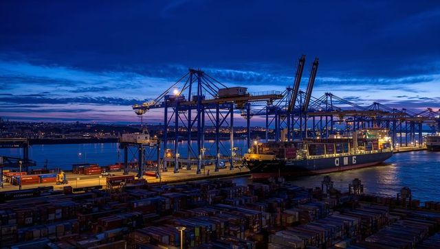 Blue hour container port unloading with illuminated gantry cranes and cargo ship