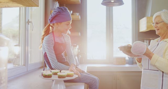 Grandmother and granddaughter baking cupcakes in sunny kitchen - Download Free Stock Images Pikwizard.com