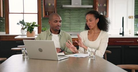 Couple collaborating at home with laptop and documents