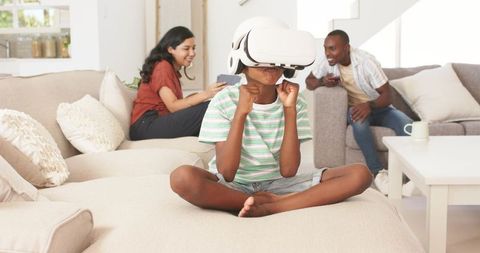 Child experiencing virtual reality on VR headset while family watching and smiling