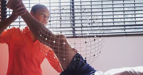 Clinician supporting patient shoulder mobilization with wireframe globe overlay for rehab