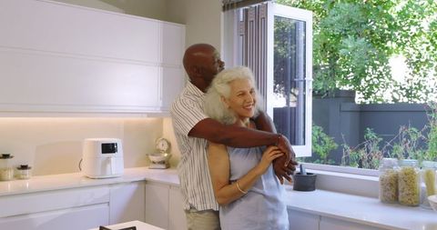 Happy senior couple hugging in cozy kitchen with natural light