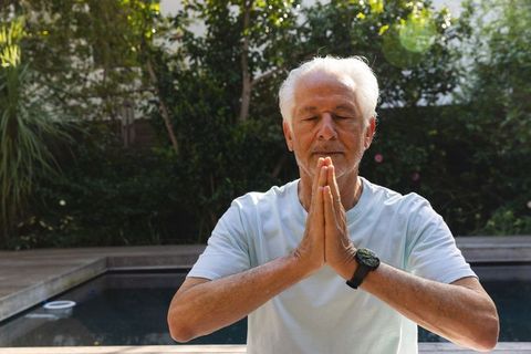 Senior Man Meditating Outdoors by Pool