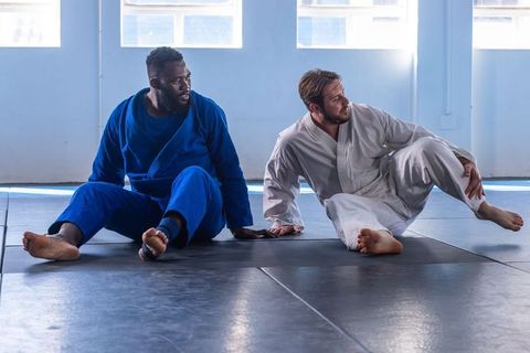 Martial arts partners stretching in dojo, traditional gis attire