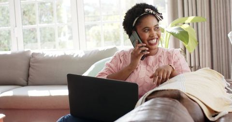 Cheerful African American Woman Talking on Phone While Using Laptop at Home - Download Free Stock Images Pikwizard.com