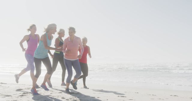 Group of senior women jogging together on sunny beach. Promotes active aging, companionship, friendship, retirement activities. Ideal for wellness, senior health, exercise routines, active elderly lifestyle promotions.