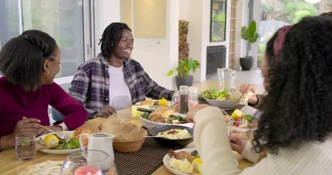 Family sharing home-cooked meal around sunlit modern wooden dining table