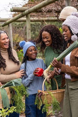 Multigenerational african american family harvesting vegetables in community garden