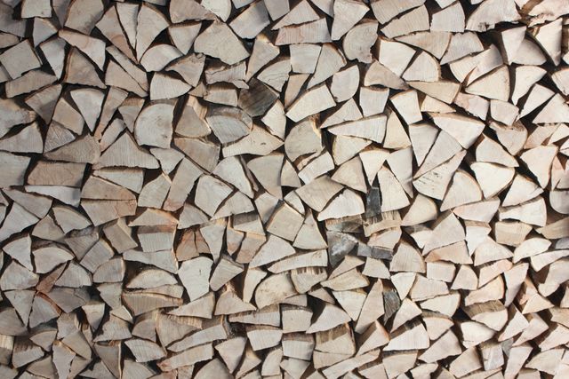 Pile of neatly stacked firewood logs forming rustic background. Perfect for themes related to winter preparation, home heating, and natural fuel sources. Suitable for blogs, websites, or advertisements focusing on rural lifestyle, sustainable energy, and home decor.