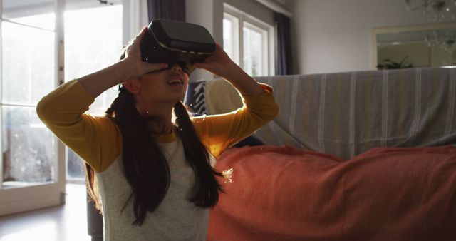 Happy asian girl at home, sitting on floor in living room using vr headset. at home in isolation during quarantine lockdown.