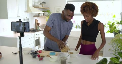Black couple cooking healthy breakfast together in bright contemporary kitchen