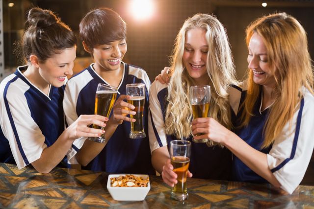 Group of friends enjoying drinks and toasting at a bar. Ideal for use in advertisements, social media posts, and articles related to social gatherings, nightlife, friendship, and leisure activities.
