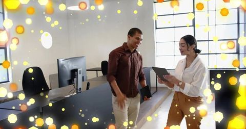 Coworkers collaborating over tablet in modern open-plan office with hex bokeh overlay