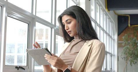 Indian Businesswoman Using Tablet Near Office Windows in Modern Coworking Space