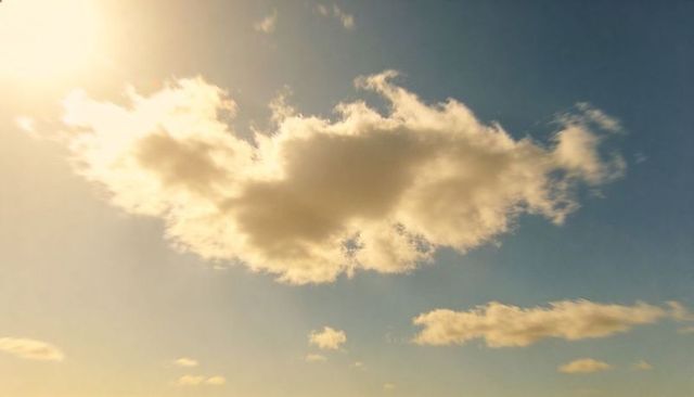 Golden-hour cumulus cloud floating over pastel gradient sky with warm sunlight glow