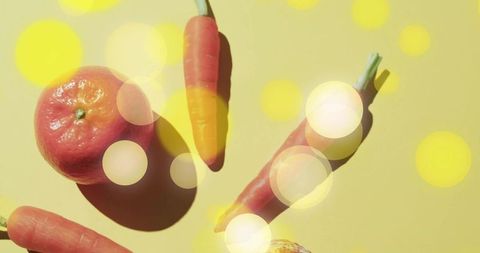 Tangerine and carrots arranging on pale yellow backdrop with soft bokeh and shadows