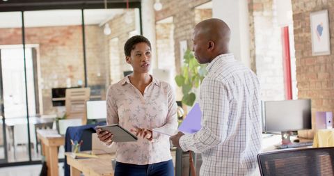 Colleagues Engaged in Discussion with Tablet in Modern Office