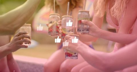 Friends clinking mason jar drinks at pool edge with social likes overlay