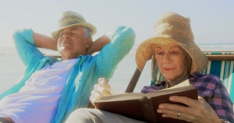Senior Couple Relaxing on Beach with Book in Leisure Time