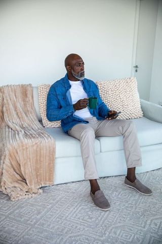 Senior Man Enjoying Coffee While Browsing Phone at Home