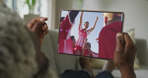 Man Streaming Soccer Match on Tablet Displaying Diverse Team