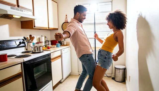 Couple dancing and swaying in sunlit kitchen, playful morning romance and home cooking