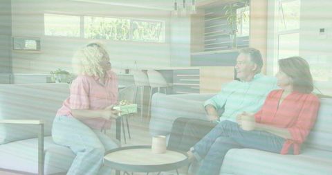 Presenting wrapped gift to smiling couple in modern open-plan living room